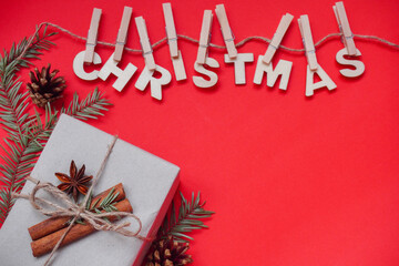 Fototapeta na wymiar Christmas composition or ornament on red background from wooden inscription Christmas, cones, wooden Christmas tree, candles and branches of spruce. Copy space, space for text, flatly.