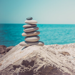 Stones pyramid on sand symbolizing zen, harmony, balance. Ocean at sunset in the background