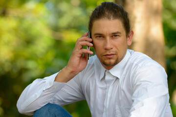 Handsome bearded businessman with long hair at the park