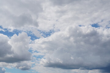White light fluffy clouds in a blue sky with a solar flare.