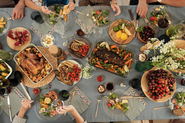 High angle view of festive table with different delicious dishes with people sitting around and eating