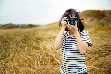 young brunette girl photographer taking picture at wheat field