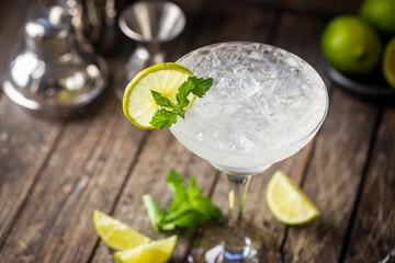 Cocktail margarita garnished with lime and mint on wooden background