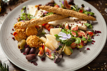 Cheese platter for two: Goat cheese cream, gorgonzola, camembert, grissini and fig jam. Delicious healthy Italian traditional food closeup served for lunch in modern gourmet cuisine restaurant
