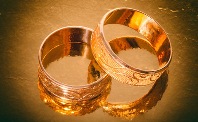 wedding rings with patterns on a golden mirror background,