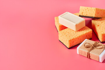 Heap of bricks of soap in vintage packing and sponges on pink background. Hygiene and cleaning concept