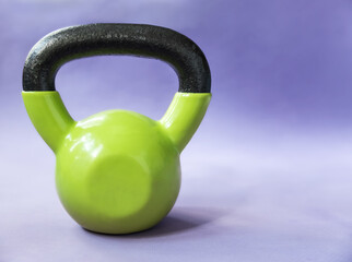 Naklejka na ściany i meble Green kettlebell on purple background. Concept of healthy lifestyle.