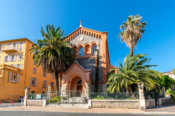 Fototapeta na wymiar The picturesque Reformed Protestant Church of France surrounded by palm trees in the Mediterranean city of Menton, France.