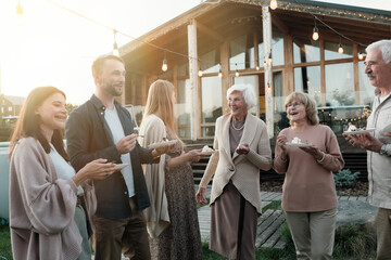 Happy big family eating cake and laughing while standing on fresh air