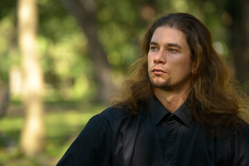 Handsome bearded businessman with long hair at the park