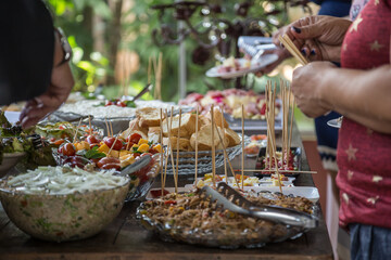 Pessoas se servindo em mesa de buffet em festa.