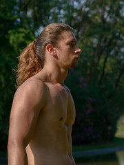 Handsome bearded businessman with long hair shirtless at the park