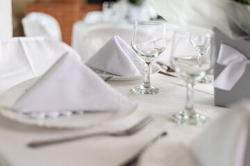 Mesa de convidados com forro branco, pratos, copos e guardanapos.