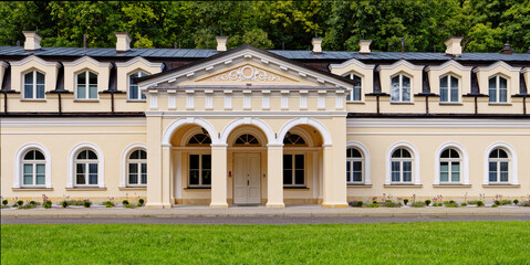 Facade of neoclassical architecture style building in European town. Sunny day in park in Naleczow health resort in Poland.