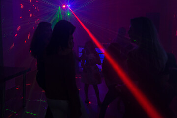 Ambiente de boate, com luzes coloridas e várias pessoas dançando.