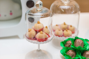 Docinhos em pequenas redomas de vidro, arranjados sobre mesa decorada para festa.