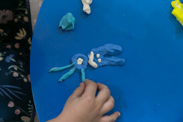 Mãos de criança modelando um coelhinho de massinha.