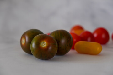 Black Zebra heirloom tomatoes with cherry tomatoes in background.