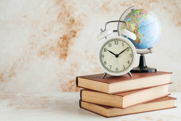 Alarm clock and globe on books. The concept of starting school, travel time. Copy space.