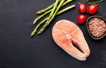 Salmon fish on the black background with asparagus  and cherry tomatoes.  Steak on black background.