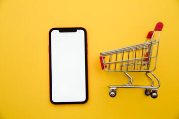 Online shopping concepts with mockup trolley and smartphone on yellow background. Ecommerce market. Transportation logistic. Business retail.