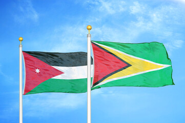 Jordan and Guyana two flags on flagpoles and blue cloudy sky