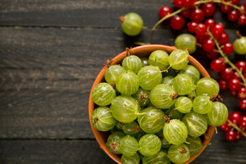 Green berry in a bowl on a dark wooden background.