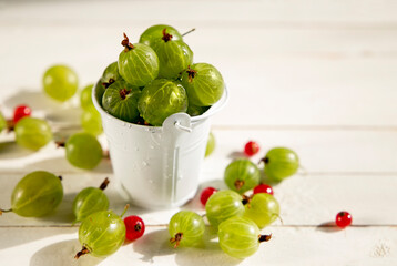 Green berry in a white bowl on a white wooden table.