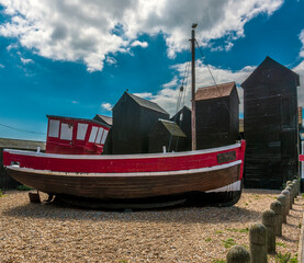 Fototapeta na wymiar A brightly coloured fishing boat in front of the net drying sheds in the old town of at Hastings, Sussex, UK in summer
