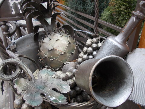 Stylish metal forging depicting a bunch of grapes, pineapple, a bottle of wine and a glass