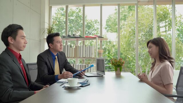 An Asian woman is interviewing a job, which she to be shaking hands from the interviewer and expecting to get a job.
