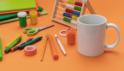 Mug white color and school supplies on orange background. Kids homework soft drink
