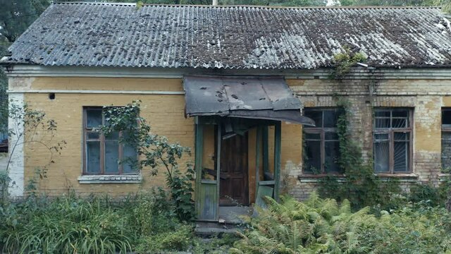 Abandoned single-family home (detached home or detached house) with broken windows among a forest