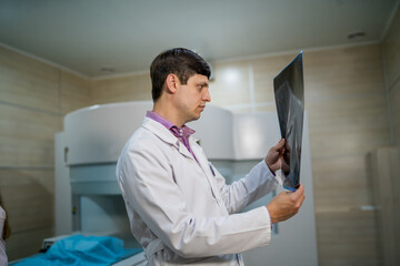 Naklejka na ściany i meble Competent doctor reading x-ray near the magnetic resonance imaging machine.