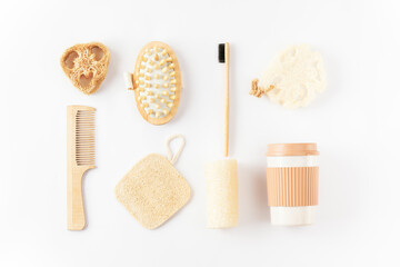 Reusable eco friendly items on white surface. Bamboo toothbrush, detangling hair brush, coffee mug, exfoliating loofah sponge, massaging brush. Sustainable lifestyle. Zero waste, plastic free concept