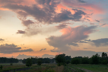 Rural landscape with dramatic clouds over the horizon. Dynamic sky with clouds illuminated by the sun