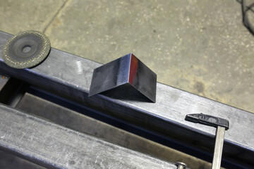 Locksmith holds an iron corner after grinding. Zapiska after welding.
