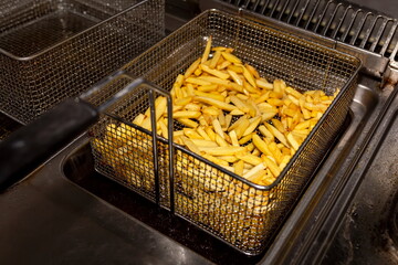 French fries in a deep fryer closeup. We drain the oil.
