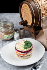 A formed portion of fat layered festive salad, russian dressed herring, served on a big white plate in a russian restaurant, classic menu photo