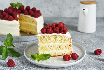 Slice of cake. Birthday cake with cream cheese and raspberries and mint on a concrete kitchen background.
