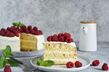 Slice of cake. Birthday cake with cream cheese and raspberries and mint on a concrete kitchen background.