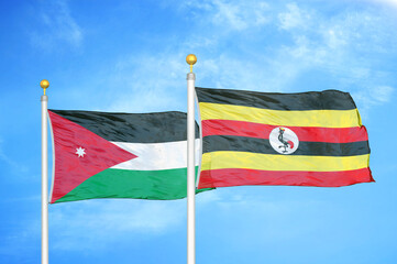 Jordan and Uganda two flags on flagpoles and blue cloudy sky