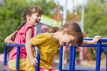 Fotobehang twee kleine meisjes lachen op een schommel in het park © Albert Ziganshin