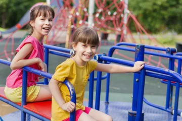 Fotobehang two little girls laughting on a playground © Albert Ziganshin