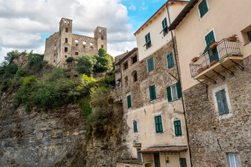 Fototapeta na wymiar The ancient hilltop castle of Dolceacqua, Italy, and walled apartment houses in the Imperia Ligurian region, on a partly cloudy day
