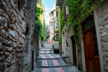 Tourists including a young couple walk up the narrow street path in the medieval village of...