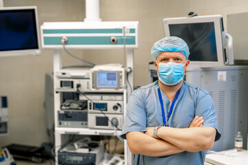 Portrait of surgeon in scrubs standing in operating theatre. Portrait of male doctor in modern medical room.