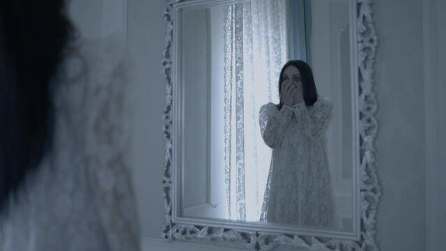 Shocked woman looking at possessed female in front of mirror, split personality
