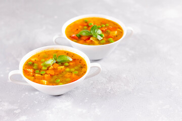 Vegetable soup with spices and basil on a light stone background. Сopy space.
