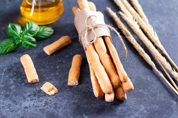 Organic Italian grissini or salted bread sticks and bread lying on a dark background